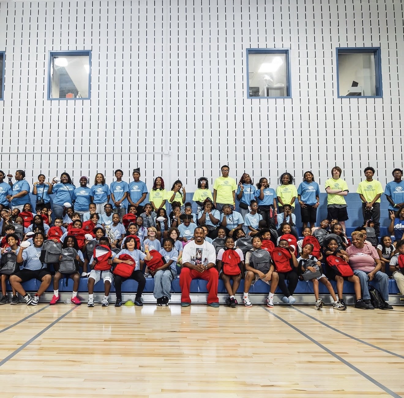 Large group photo of Nick Cross with dozens of Boys & Girls Clubs kids holding new backpacks