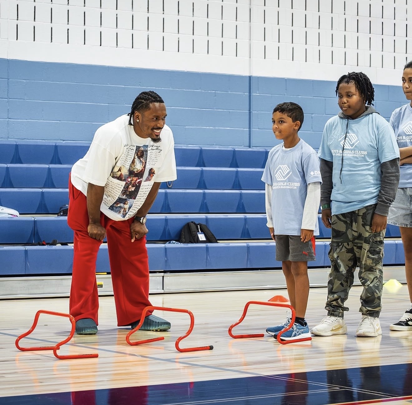 Nick Cross laughing with Boys & Girls Clubs kids at a hurdle agility drill