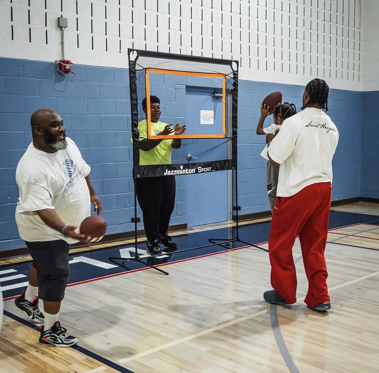 Nick Cross running a football throwing-target drill with kids and staff in the gym