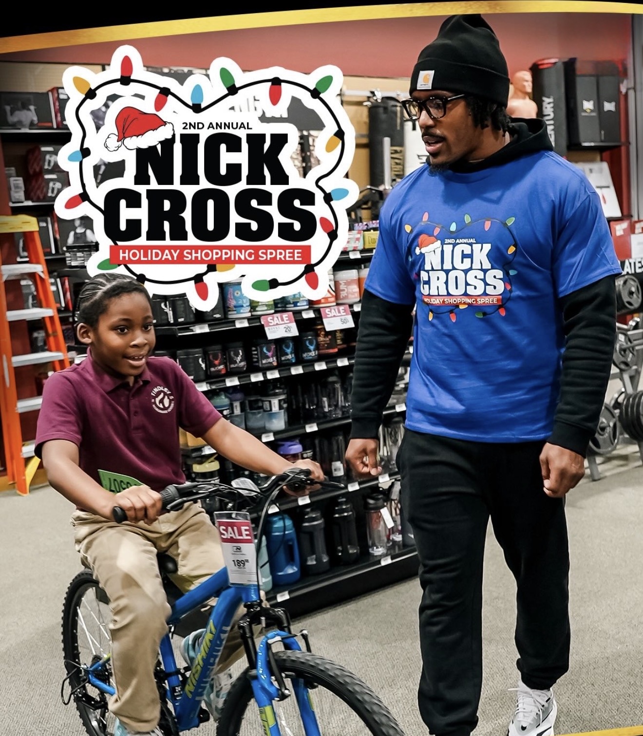 A boy on a new blue bike beside Nick Cross at the Holiday Shopping Spree