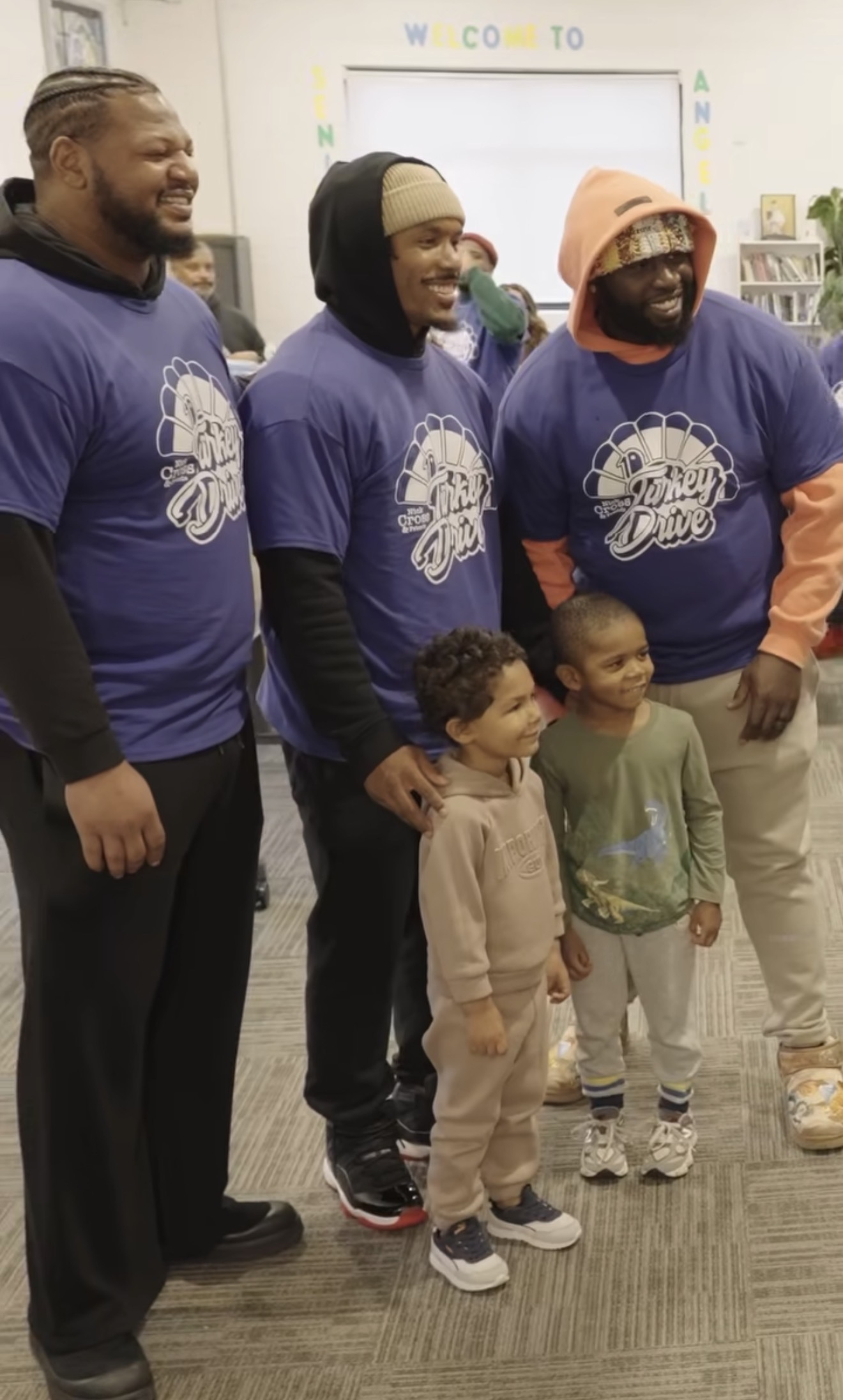 Nick Cross with two other volunteers in Turkey Drive shirts posing with two young boys